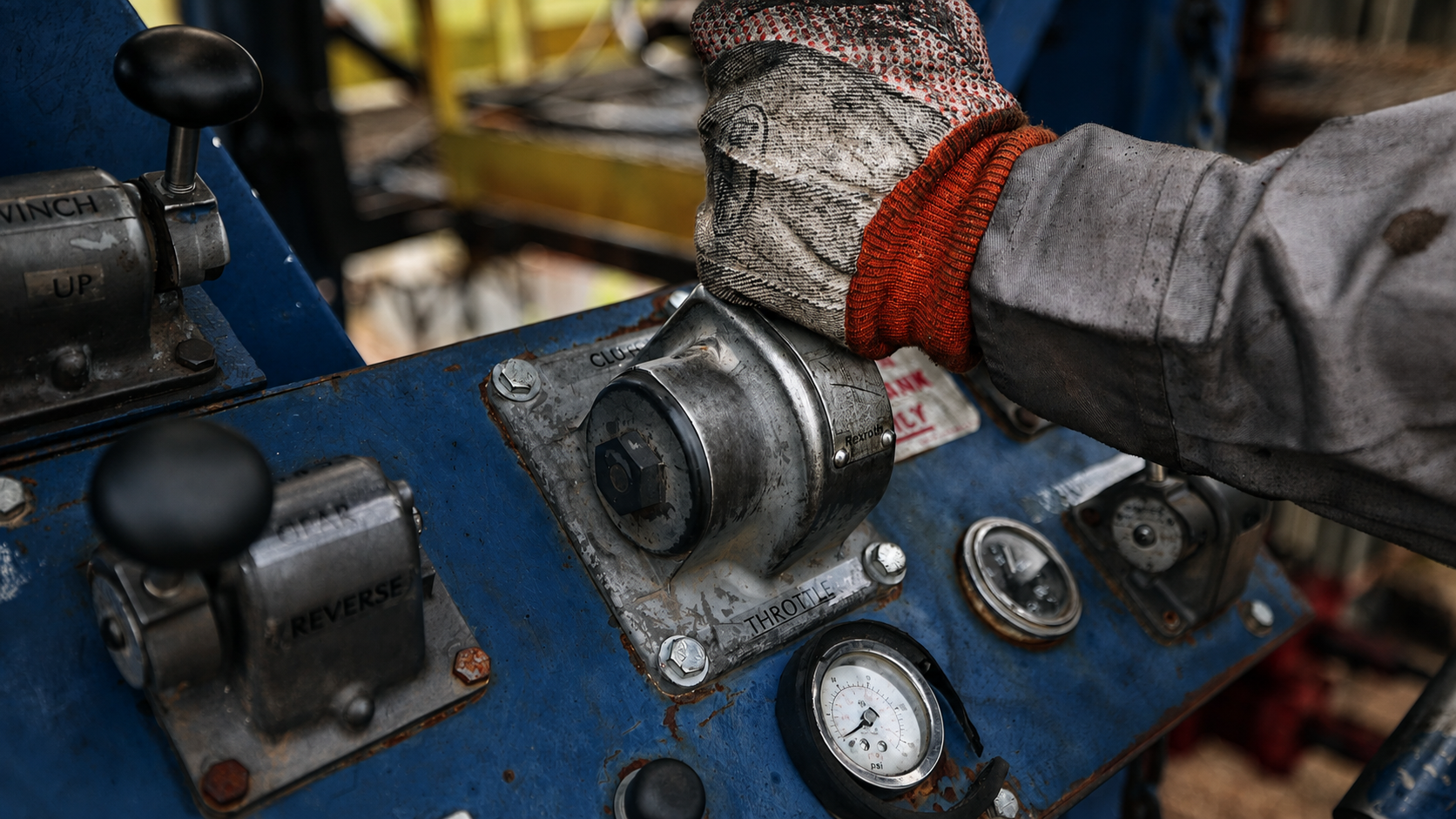 Gloved hand of a Rise Drilling crew member on the rig throttle and clutch controls