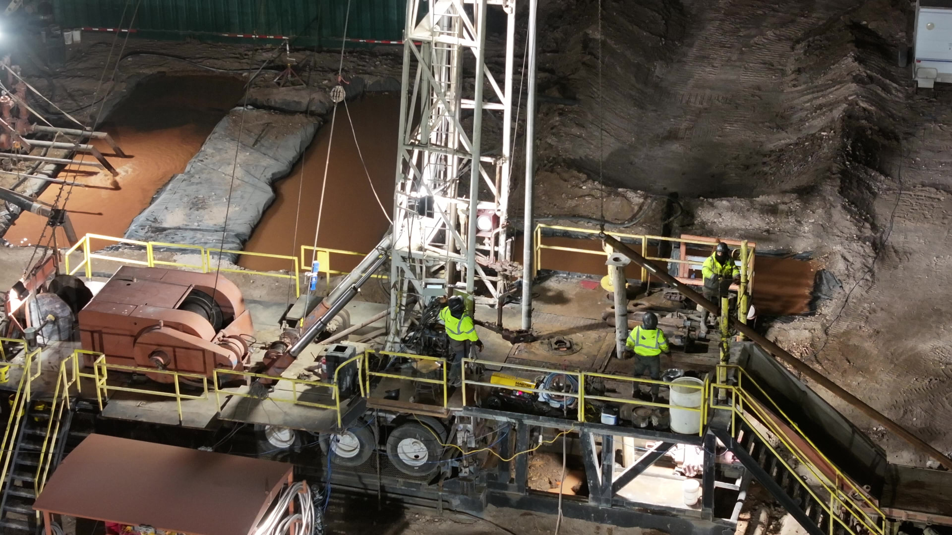 Aerial night view of a Rise Drilling rig floor with crew members working under lights
