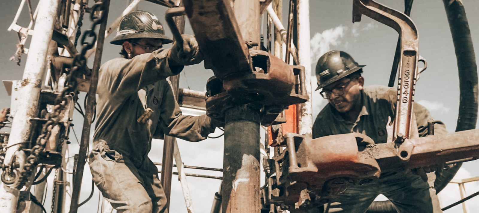 Rise Drilling floorhands making a connection with tongs on the drill string