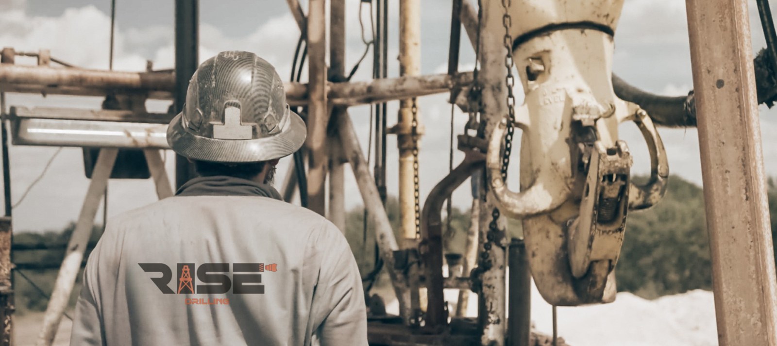 Rise Drilling crew member in branded coveralls and hard hat walking onto the rig floor